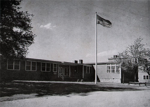 Administration Building, the Nerve Center of Wave Quarters “D”, Flies Its Flag Proudly. . . As Though in Proclamation of “D” As the Largest Wave Quarters in America . . . Representative of the Work of the Women’s Reserve in a Fighting Navy!
