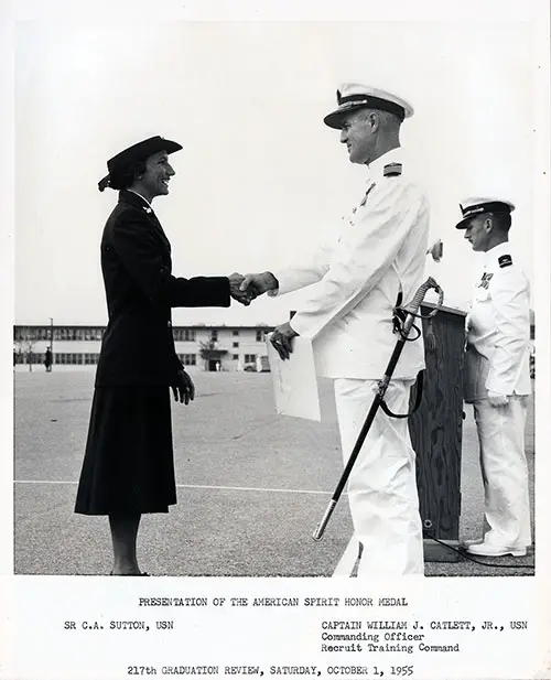 Presentation of American Spirit Honor Medal to SR C. A. Sutton, USN. Image shows Captain William J. Catlett, Jr., USN, Commanding Officer Recruit Training Command shaking hands with SR Capitolie A. Sutton, USN of 1955 Company 18(W) at the 217th Graduation Review, Saturday, October 1, 1955.