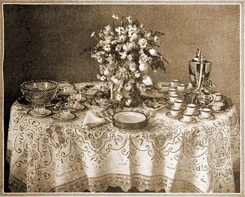 Wedding Buffet Table Set Up with Plates, Napkins, Punch Bowl and Glasses, Coffee and Coffee Cups, with a Center Floral Piece.