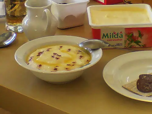 Traditional Norwegian Rømmegrøt (Sweet Cream Porridge) Served in a Bowl with Melted Butter, Sugar and Cinnamon.