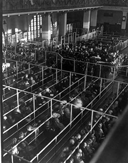Emigrants in 'pens' at Ellis Island, New York, probably on or near Christmas --note the decorations