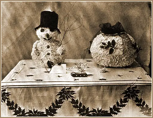 A Paper Table Cloth Makes a Gay Background and Grotesque Paper Ornaments to Never Fail To Amuse Big and Little Folks Alike.