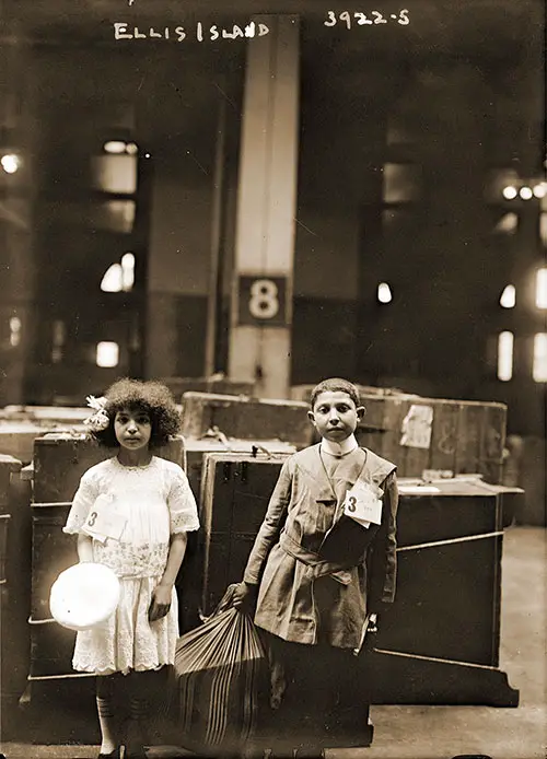 Young Children Standing in Luggage Area Eight at Ellis Island with Immigrant ID Tags Attached to Their Clothing.