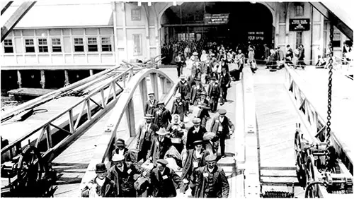 Immigrants Walking Across Pier from Bridge at Ellis Island. nd circa 1910s.