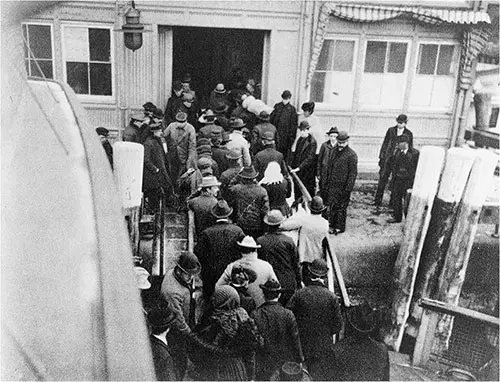 The landing of the New Immigrants Passed From the Ferry-Boat Which Brings Them From Ellis Island to the Battery Outside of Barge Office in New York.