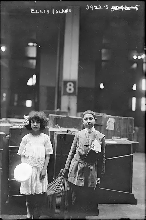 Two Young Immigrants Standing in Front of Luggage Section 8 at Ellis Island circa 1915.