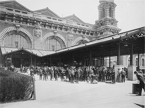 Immigrants Standing Outside the Main Building at Ellis Island circa 1910.