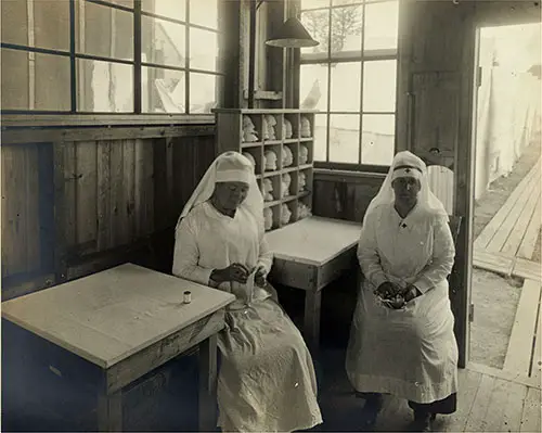 Two Red Cross Workers Relax in Mask Storage Room at Influenza War Camp, Emery Hill, Lawrence, Massachusetts circa 1918-1919.