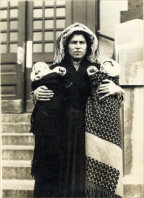 Immigrant Woman of Unknown Nationality Holds Two Children, One in Each Arm at Ellis Island.
