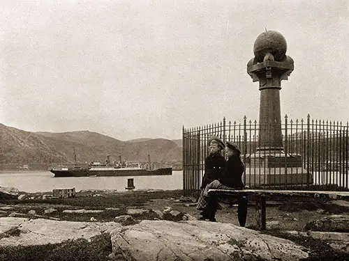 Two Children Sit by the Meridian Column at Hammerfest with the SS Blücher in the Background.