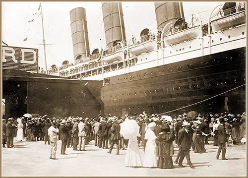 Lusitania - Arriving in New York City; Close-up of Starboard Side at Dock Showing Crowd Gathered on Pier.