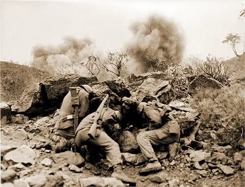 Korean Conflict. Men of the 3rd Battalion, 34th Infantry Regiment, 35th Infantry Division, covering up behind rocks to shield themselves from exploding mortar shells, near the Hantan River in central Korea, 11 April 1951.