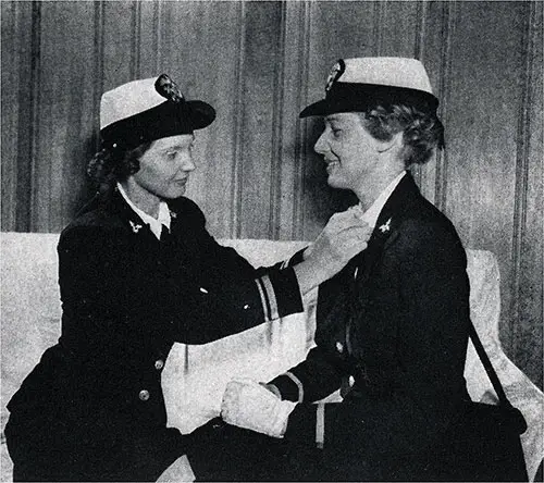 Lt, (j.g.) Enright adjusts the collar insignia of Ensign Foster. Official Navy Photo.