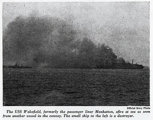 The USS Wakefield, formerly the passenger liner Manhattan, afire at sea as seen from another vessel in the convoy.
