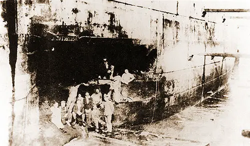 Workers Pose by the Torpedo Damage to Finland in Drydock at Brest, France.